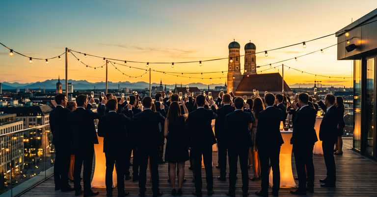 Dachterrassen-Firmenfeier über München: Gäste beim Toast vor der Skyline mit Frauenkirche und Alpen